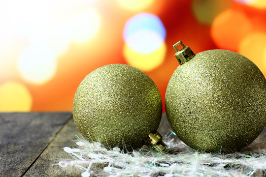 Christmas background with gold balls decorations on old dark wooden desk table. Colorful holiday bokeh garland lights. Wood foreground and ready for product montage. White copyspace on top corner.