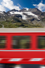 Fototapeta premium Red train in motion and the Bernina Alps, Engadine, Switzerland, Europe