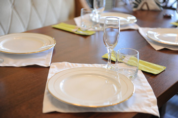 Served table in restaurant. White plates, glasses on a white cloth on wooden surface