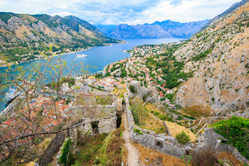 Fototapeta na wymiar Panoramic view of old town, ruin of medieval fortifications, stone walls of ancient fortress and mountain landscape in Bay of Kotor, Montenegro.