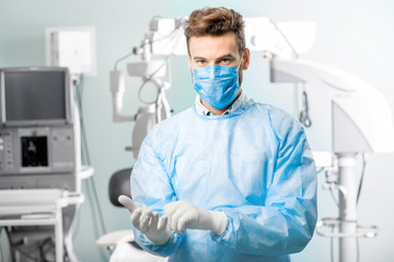 Fototapeta na wymiar Surgeon wearing gloves in the operating room with surgical microscope on the background