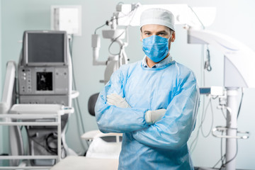 Fototapeta na wymiar Portrait of surgeon in operating room with surgical microscope on the background