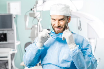 Portrait of happy surgeon in operating room with surgical microscope on the background