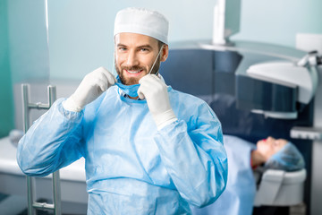 Portrait of eye surgeon in the operating room with patient and laser machine on the background. Laser vision correction