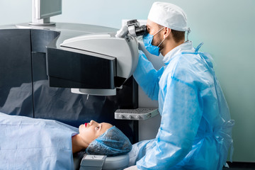 Eye surgeon operating woman with laser vision correction machine in the operating room