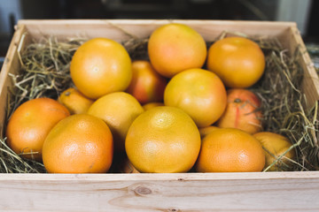 Wooden box with fresh ripe grapefruits on display in a fruit sho