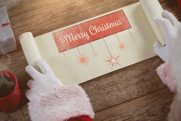 Composite image of close-up of santa claus opening scroll