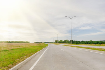 Asphalt road with a dividing strip and car in the sunlight