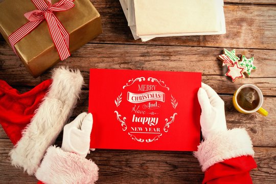 Composite image of santa claus holding a red placard