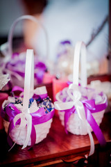 Wedding accessories in violet colors on the table. Ring candle shoes at wooden background