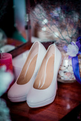 Wedding accessories in violet colors on the table. Ring candle shoes at wooden background