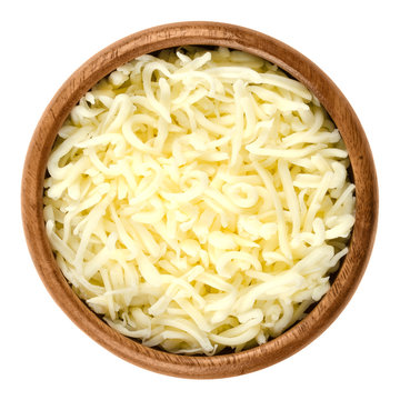 Shredded mozzarella pizza cheese in wooden bowl over white. Cheddar like semi hard Italian cheese made from milk, covered with corn starch. Isolated macro food photo close up from above.