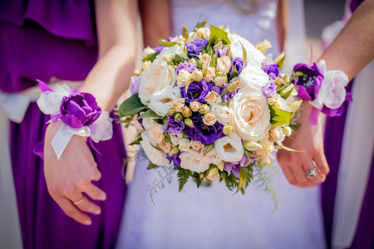 bride and bridesmaids with violet bracelets on hands