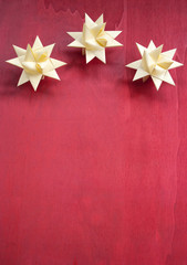 Weihnachtssterne aus Papier gefaltet auf rotem Holz Hintergrund, Weihnachten, xmas, Textfreiraum