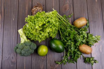 salad, kiwi, lime, broccoli, parsley and avocado lie on the tabl