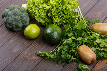 salad, kiwi, lime, broccoli, parsley and avocado lie on the tabl