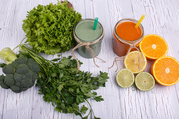 green and orange detox coctails stands on white table with fruit
