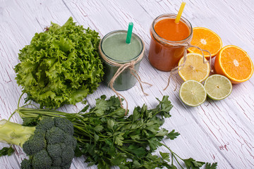 green and orange detox coctails stands on white table with fruit