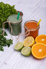 green and orange detox coctails stands on white table with fruit