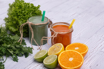 green and orange detox coctails stands on white table with fruit