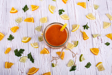 orange smoothie stands on white table with many small pieces of
