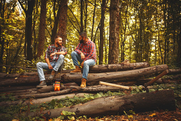 Two friends Lumberjack worker sitting in the forest .Resting after hard work. - Powered by Adobe