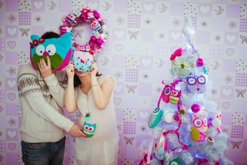 Fototapeta premium pregnant woman with her husband hiding behind the soft owls