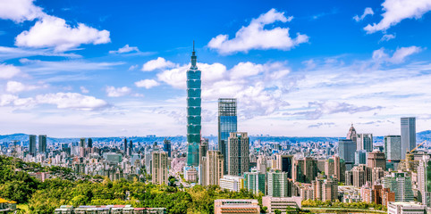Aerial panorama over Downtown Taipei, capital city of Taiwan with view of prominent Taipei 101 Tower amid skyscrapers in Xinyi Financial District & overcrowded buildings in city center under sunny sky