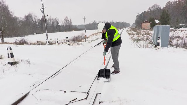Railroad employee clean snow on railway crossing