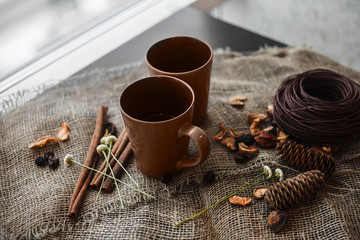 Autumn composition: 2 cups, cinnamon, pinecones on the canvas cl