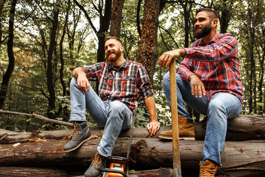 Two friends Lumberjack worker sitting in the forest .Resting after hard work.
