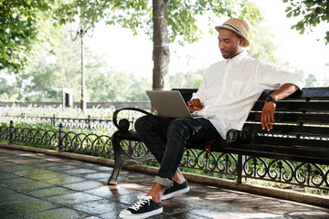 Fototapeta premium Smiling hipster with laptop in park
