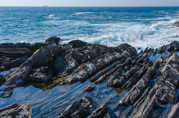 clear blue sea water trapped in stone at the rocky shore of Geno Nervi in front of the vast Mediterranean