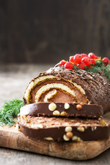Chocolate yule log christmas cake with red currant on wooden background
