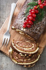 Chocolate yule log christmas cake with red currant on wooden background.closeup
