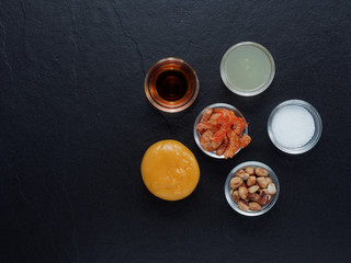 Mix ingredients of Thai green papaya salad (Som tum) composed of dried shrimp, peanut, plum sugar, lime juice, seasoning powder, and fish sauce on dark background
