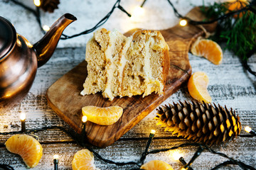 New Year's dessert - a slice of cake with butter cream surrounded by colorful garlands, on a wooden...
