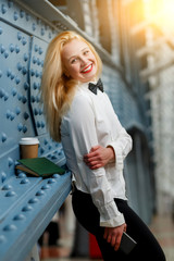 Business woman in white shirt, black pants at blue wall