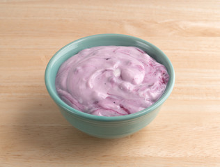 Bowl of blueberry gourmet yogurt on a wood table top.