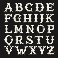 Old serif alphabet font on the dark background.