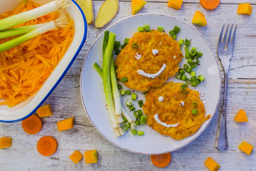 Fried fritters with pumpkin with green onions and spices on wooden background.