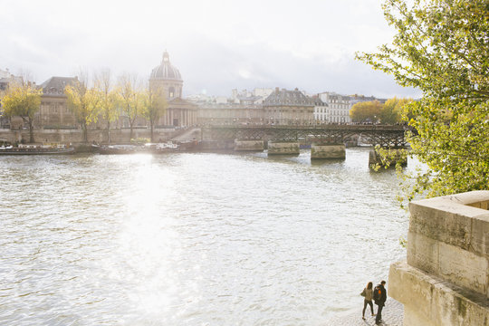 Couple walking by the River Seine in Paris near Pont des Artes Bridge