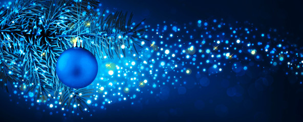Christmas ball hanging on fir branch with festive bokeh background.