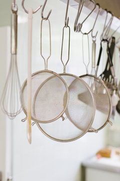 Sieves and whisks and other kitchen tools hanging in a restaurant kitchen