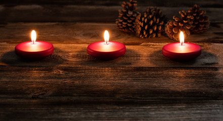 winter candlelight with glowing small red candles and fir cones