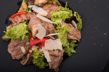 salad of veal, cheese and red pepper on black plate