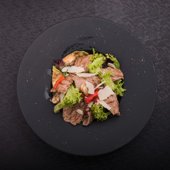 salad of veal, cheese and red pepper on black plate