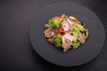 salad of veal, cheese and red pepper on black plate