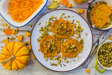 Fried fritters with pumpkin with fried sprouts and spices on wooden background. Vegetarian food.
