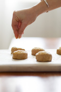 A woman's hand sprinkling sugar on some pastries